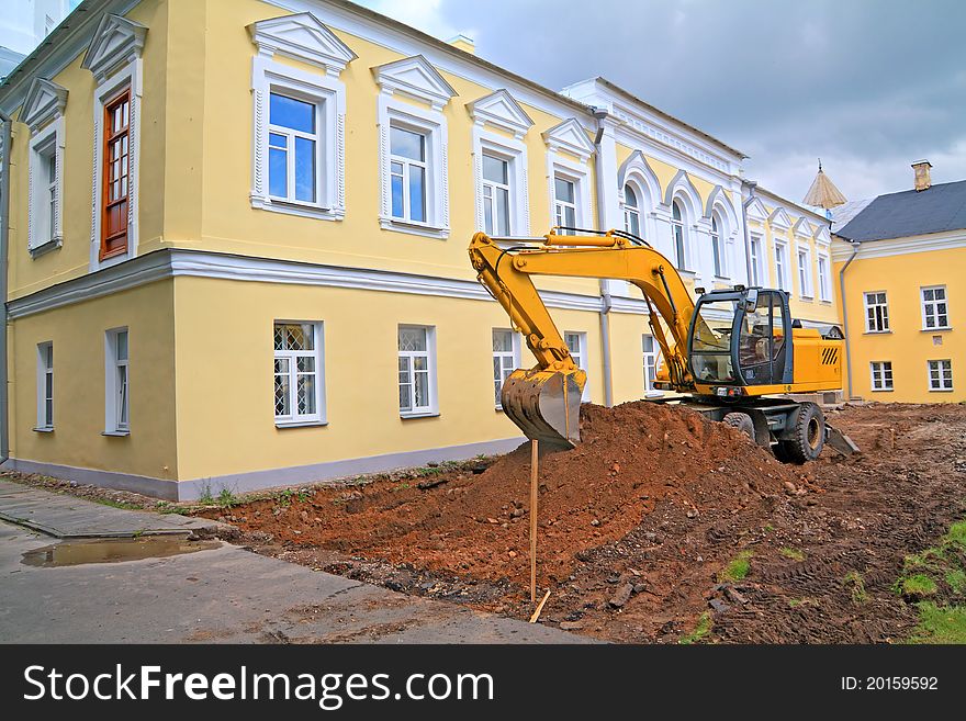 Yellow excavator near the yellow house. Yellow excavator near the yellow house