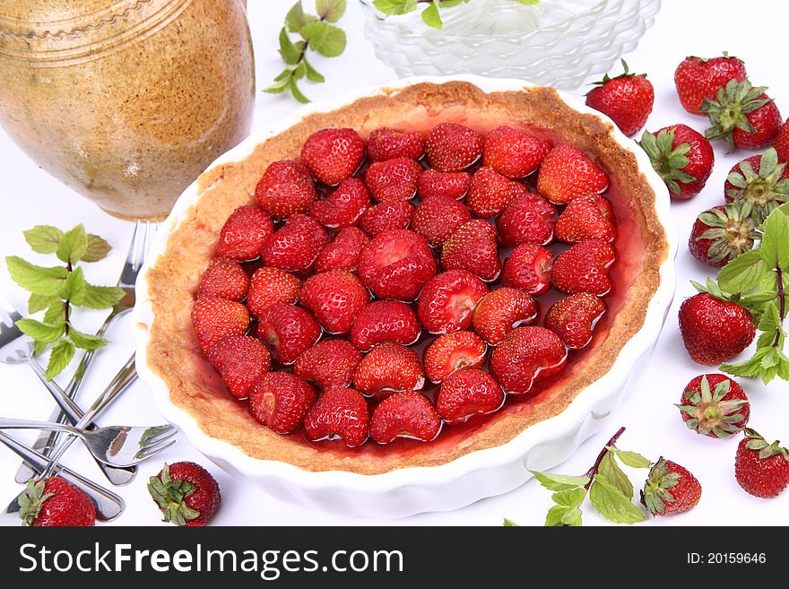 Strawberry Tart, plates, a pot, forks, strawberries and mint twigs on a white background