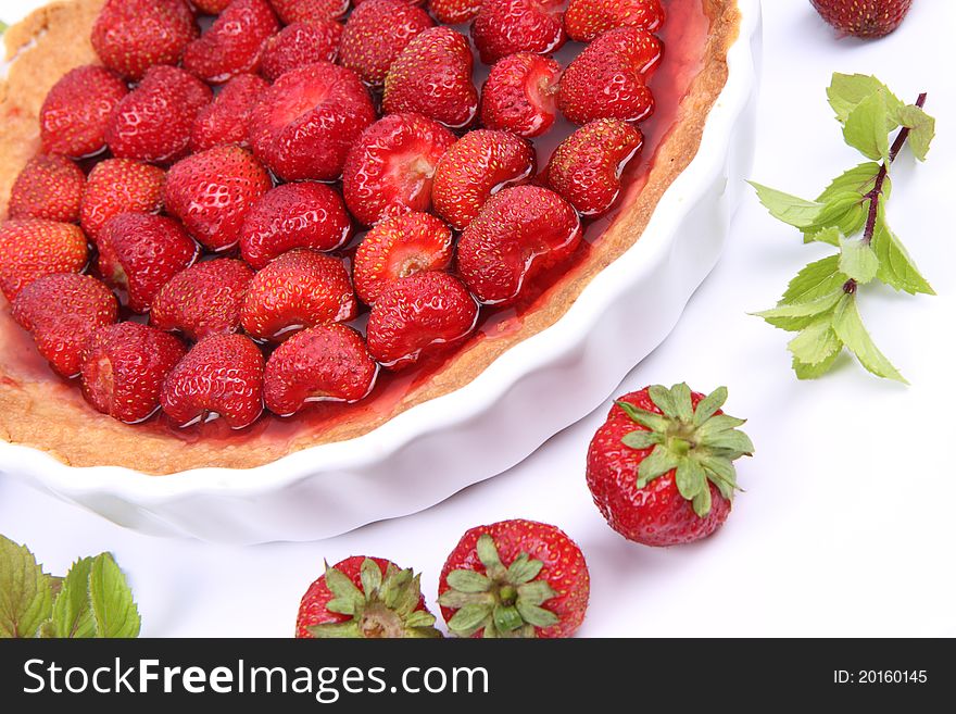 Strawberry Tart decorated with strawberries and mint twigs on a white background