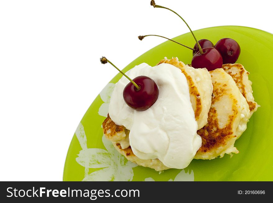 Pancakes with cherries and cream on green plate
