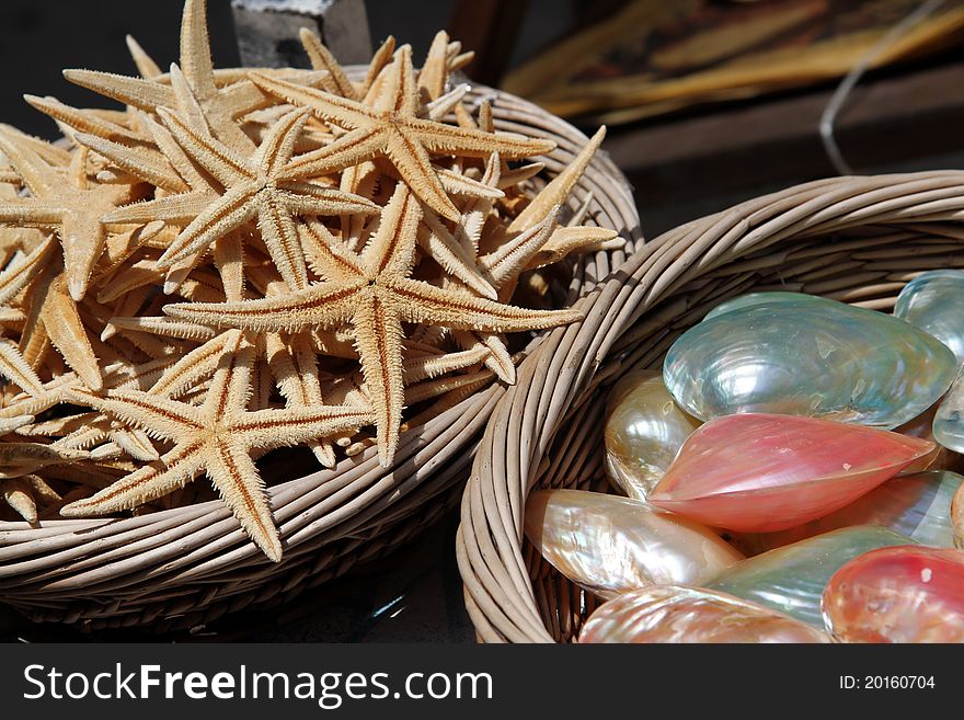 Large baskets of sea shells and star fish for sale at a sea side market. Large baskets of sea shells and star fish for sale at a sea side market.