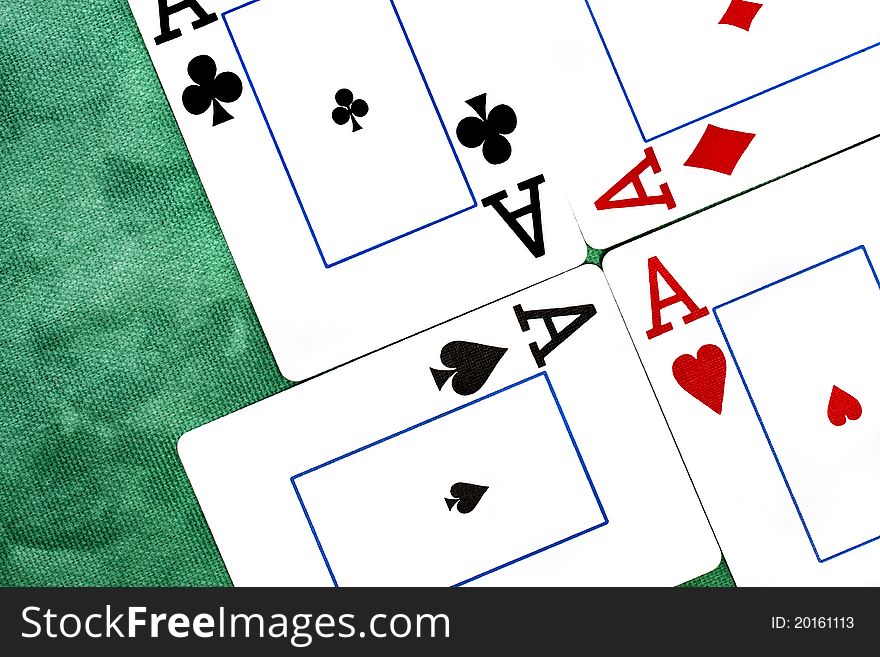 Close up view of a set of four aces spread on a green cloth table.