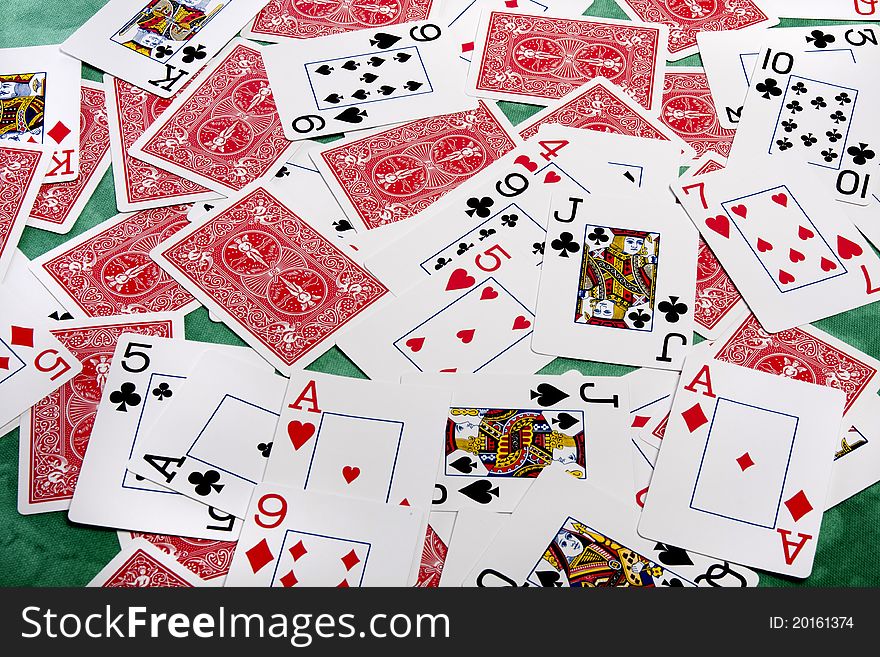 Close up view of a bunch of playing cards spread on a green cloth table. Close up view of a bunch of playing cards spread on a green cloth table.