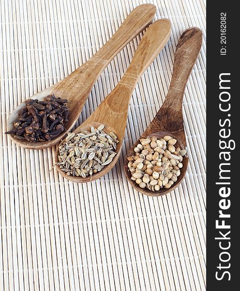 Various spices on spoons isolated on wooden background
