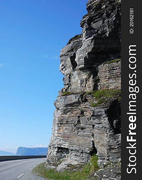 Asphalt road is meandering between blue fjord and cliff. Mageroya is an island in Finnmark county in the extreme north of Norway. Asphalt road is meandering between blue fjord and cliff. Mageroya is an island in Finnmark county in the extreme north of Norway.