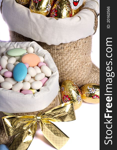 Close up view of sweet almonds and chocolate eggs inside a sack isolated on a white background. Close up view of sweet almonds and chocolate eggs inside a sack isolated on a white background.