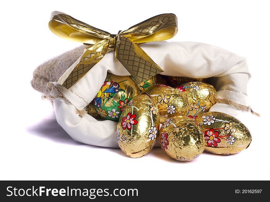 Close up view of sweet golden eggs inside a sack isolated on a white background.