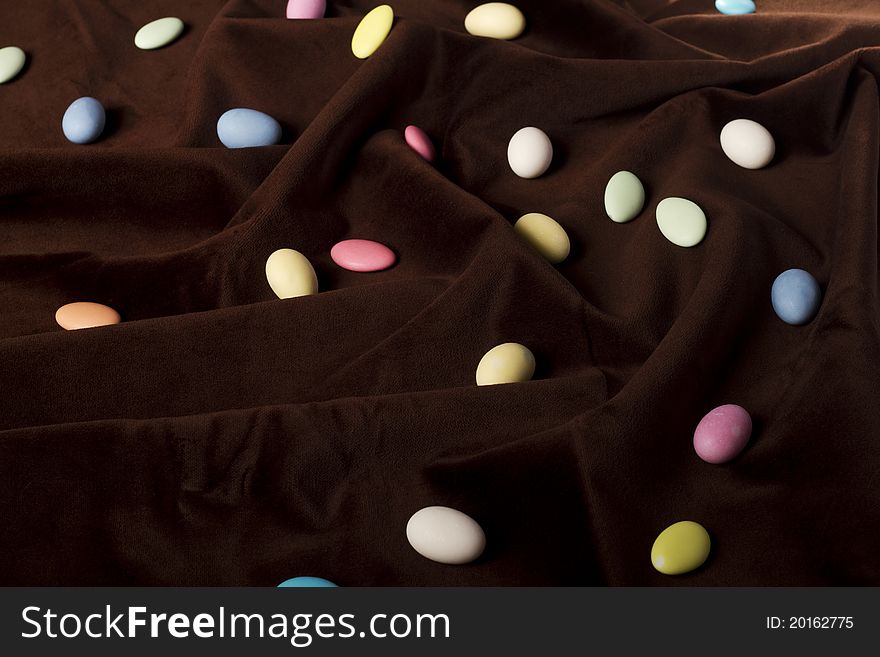 Close up view of a bunch of sweet almonds spread on a dark brown silk background.