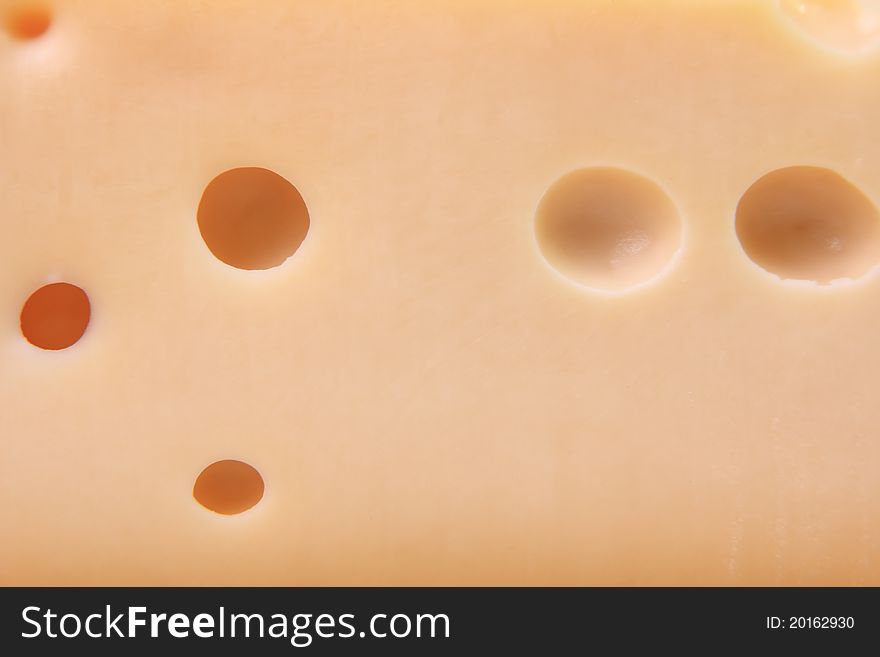 Cut cheese with big round holes close up