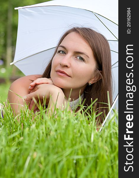 Young women with white umbrella lies on grass. Young women with white umbrella lies on grass