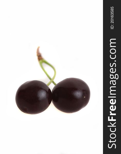 Two black cherries on a green stipe