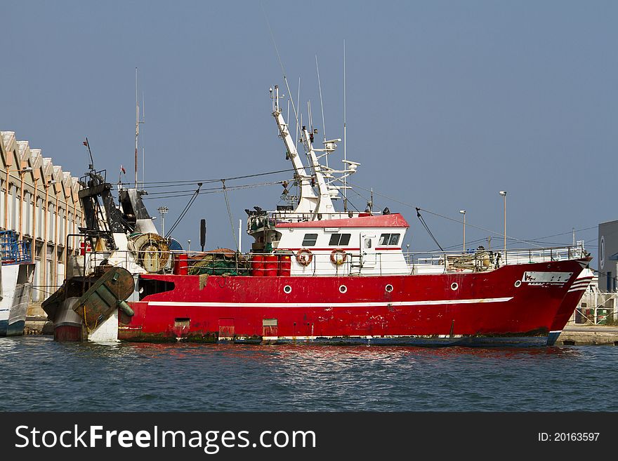 View of a red fishing boat anchored on the docks.