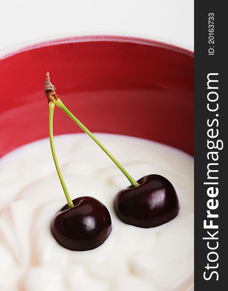 Two black cherries in a bowl with yogurt. Two black cherries in a bowl with yogurt