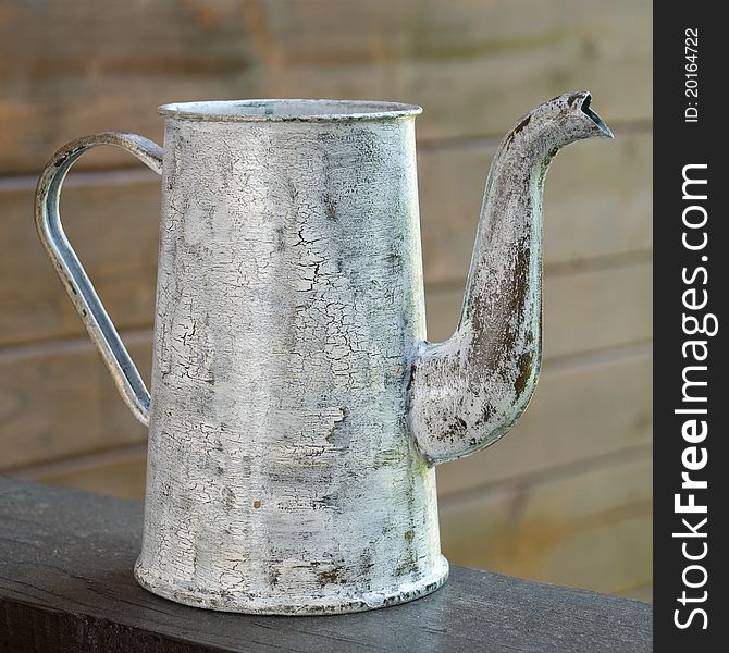 Old watering can against a wooden wall