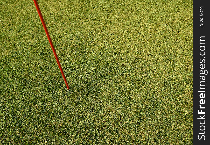 Red marking flag pole on fresh green grass field. Red marking flag pole on fresh green grass field