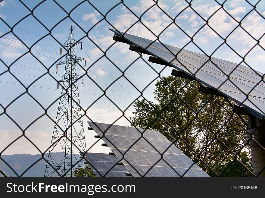 Photovoltaic panels inside a fence with power line nearby in the Tuscany green. Photovoltaic panels inside a fence with power line nearby in the Tuscany green