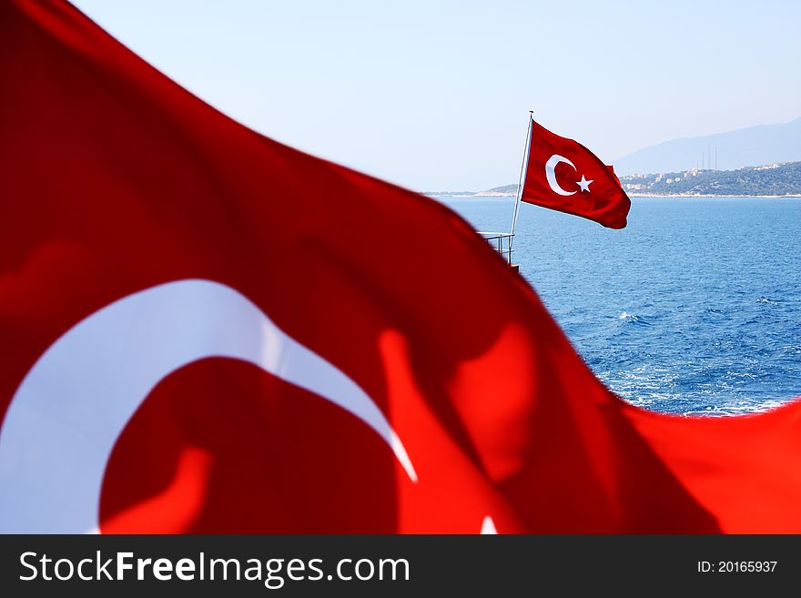 Image of two Turkish flags above sea