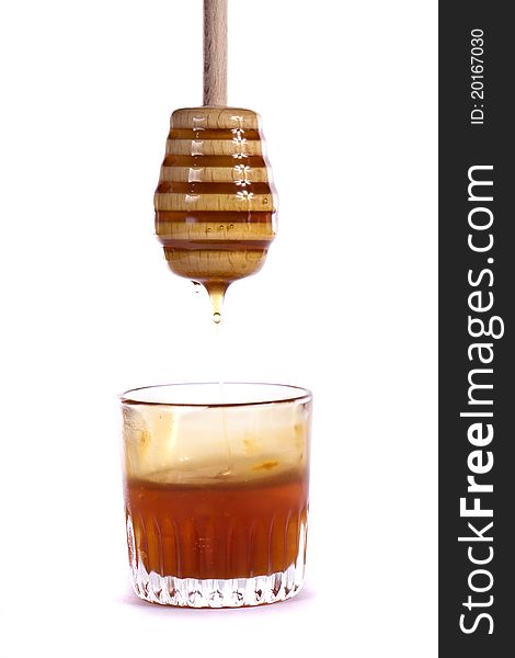 Close up view of a glass of honey with dipper isolated on a white background.