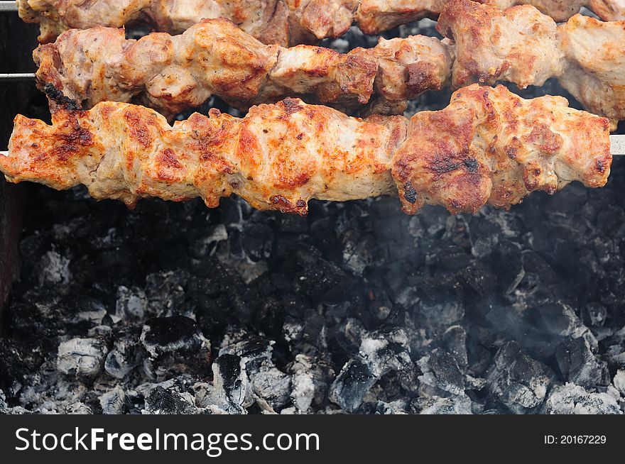 Meat on barbecue with wooden coal beneath