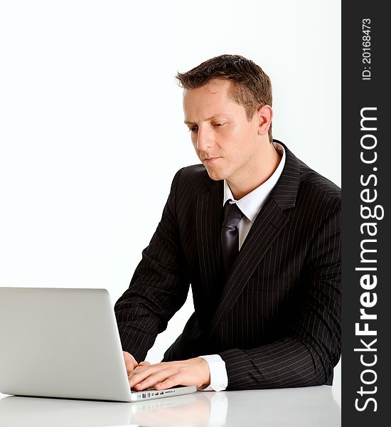 Attractive caucasian professional in a business suit works on his laptop. Attractive caucasian professional in a business suit works on his laptop