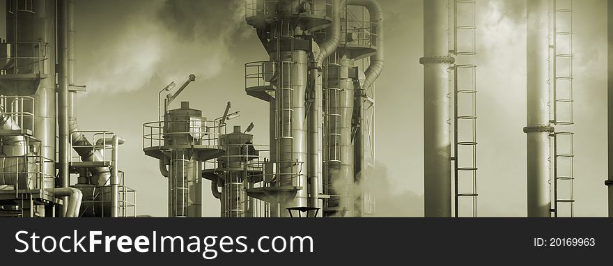 Large oil refinery surrounded by smoke and clouds, panoramic view. Large oil refinery surrounded by smoke and clouds, panoramic view