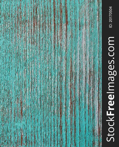 Green paint peeling from a wooden panel door showing the wood grain. Green paint peeling from a wooden panel door showing the wood grain