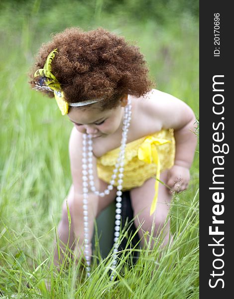 Cute toddler girl wearing a feather headband and a cute yellow petti romper