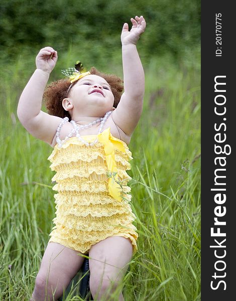 Cute toddler girl wearing a feather headband and a cute yellow petti romper