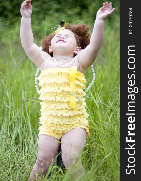 Cute toddler girl wearing a feather headband and a cute yellow petti romper