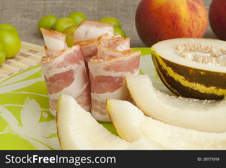 Ham with melon and peach on a green plate. Ham with melon and peach on a green plate