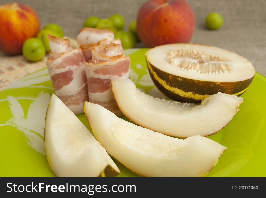 Ham with melon and peach on a green plate. Ham with melon and peach on a green plate