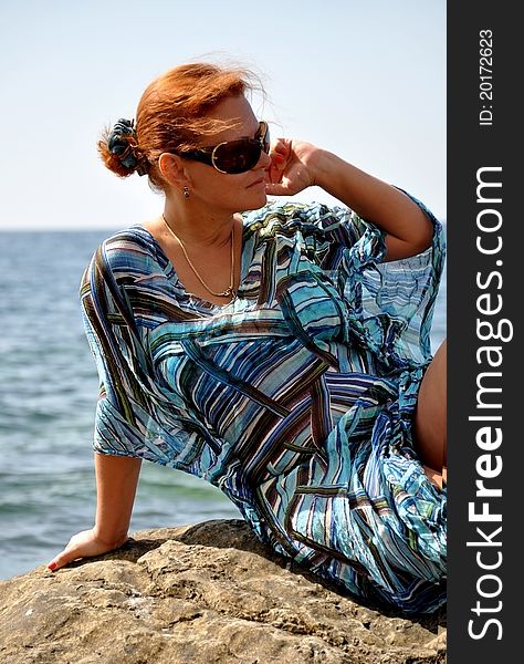 Smart woman in a blue dress against the backdrop of the sea on a luxury holiday. Smart woman in a blue dress against the backdrop of the sea on a luxury holiday