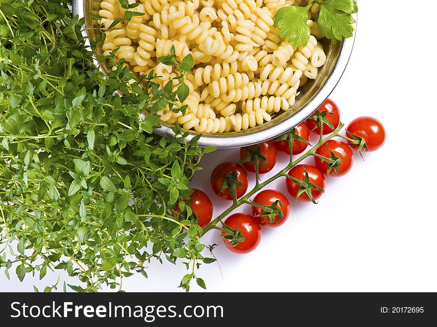 Fusilli pasta in colander with thyme and tomatoes over white background. Fusilli pasta in colander with thyme and tomatoes over white background