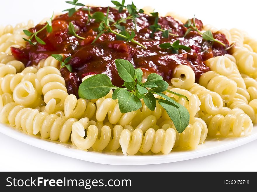 Fusilli pasta with tomato and vegetable sauce over white background