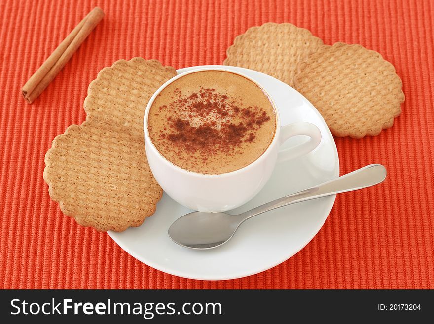 A cup of coffee with cinnamon and cookies