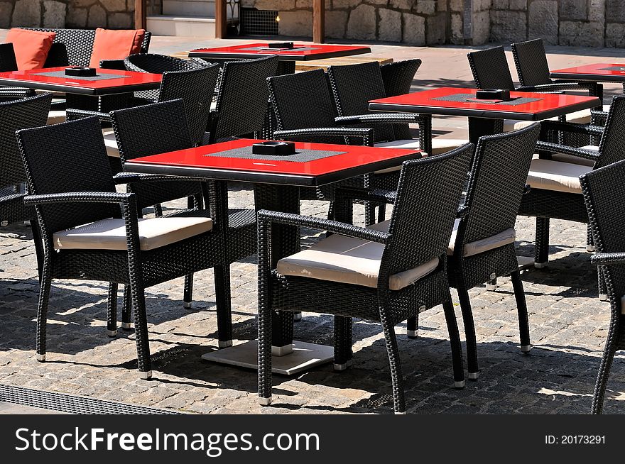 An outdoor restaurant on a sunny summers day with empty tables and open seats. An outdoor restaurant on a sunny summers day with empty tables and open seats