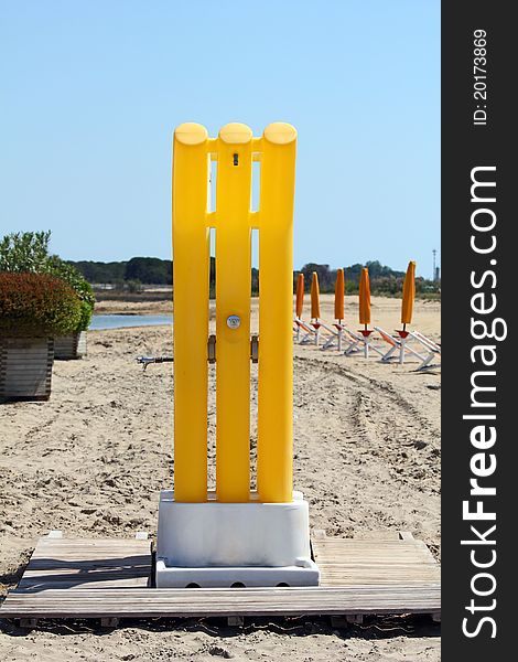 Yellow shower on the beach with sunshades in the background