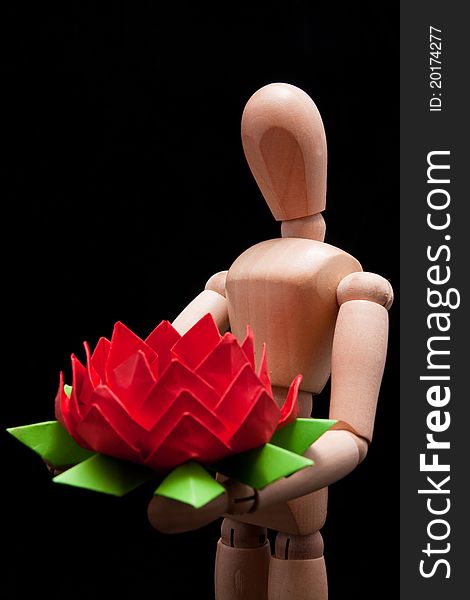 A wooden mannequin carrying hand-made paper flower. This photo made over black background but is not isolated. A wooden mannequin carrying hand-made paper flower. This photo made over black background but is not isolated.