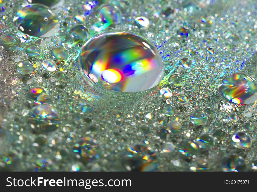 Close up view of many colorful and bright drops of water on a shiny surface. Close up view of many colorful and bright drops of water on a shiny surface.