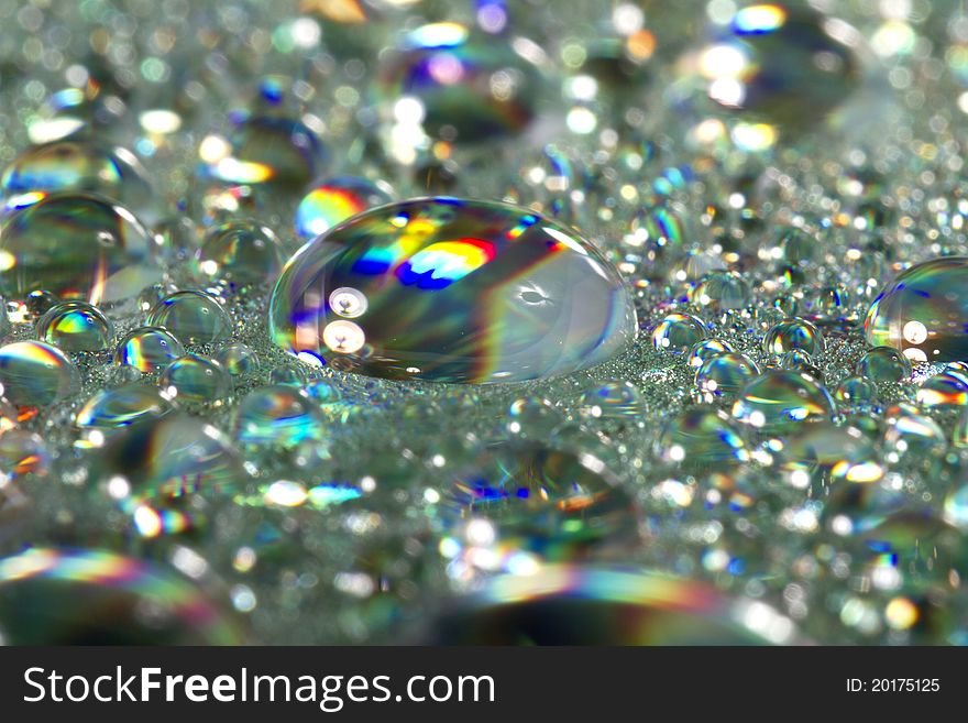 Close up view of many colorful and bright drops of water on a shiny surface. Close up view of many colorful and bright drops of water on a shiny surface.