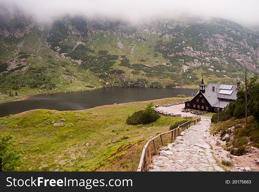 Picture shows a mountain lake and mountain hut in the fog