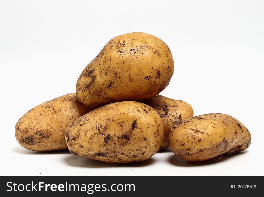 Pile, fresh dirty potatoes on a light background. Pile, fresh dirty potatoes on a light background.