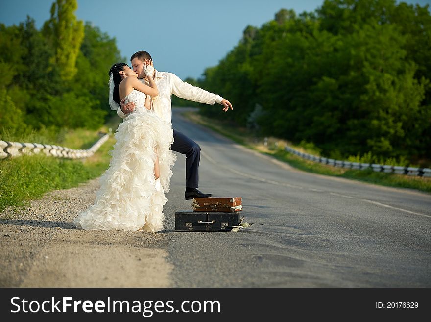 Newlywed couple hitchhiking on a road