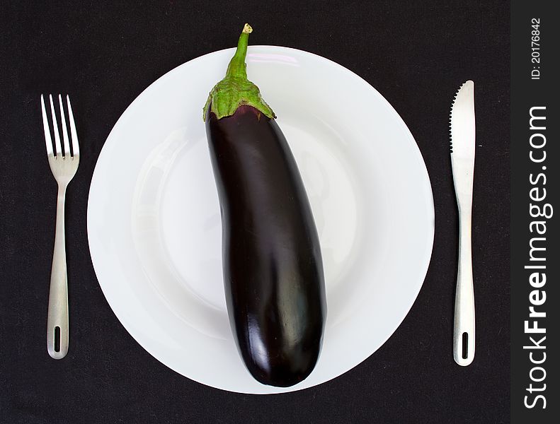 Eggplant on a white plate isolated against a dark background
