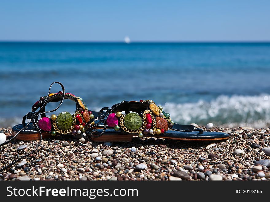 Colorful summer beachwear,open-toe sandals on sand beach. Colorful summer beachwear,open-toe sandals on sand beach