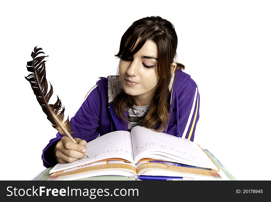 View of a teenager school girl writing on the book with a feather pen. View of a teenager school girl writing on the book with a feather pen.