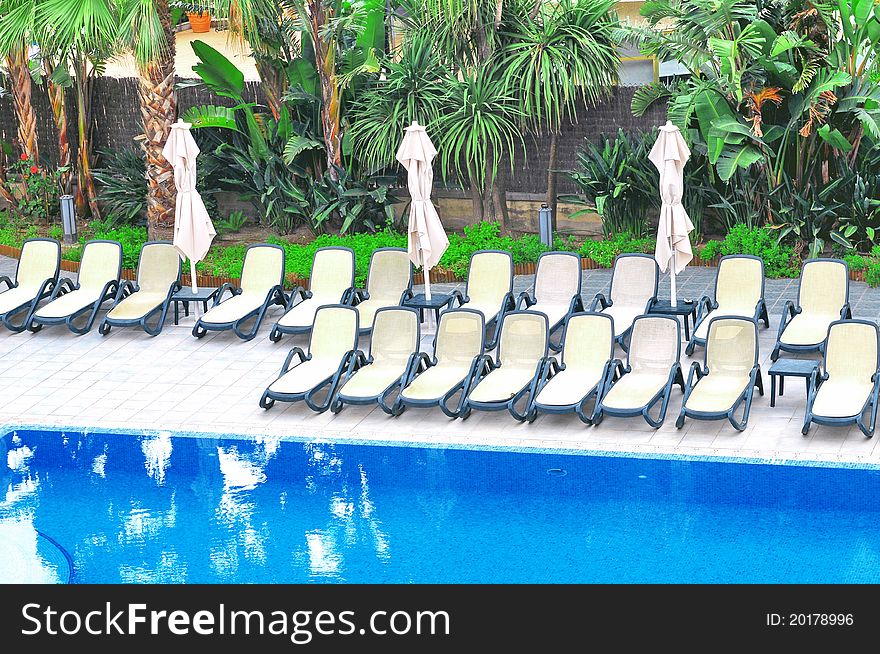 Plastic Chairs And Umbrellas Near Swimming Pool