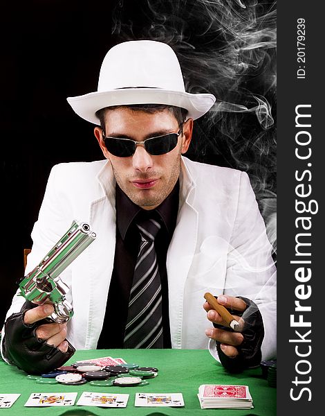 View of a gangster man playing some cards and poker, smoking a Cuban cigar. View of a gangster man playing some cards and poker, smoking a Cuban cigar.