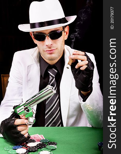 View of a gangster man playing some cards and poker, smoking a Cuban cigar. View of a gangster man playing some cards and poker, smoking a Cuban cigar.