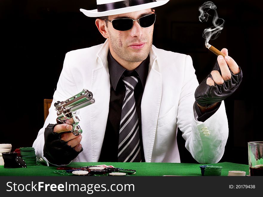 View of a gangster man playing some cards and poker, smoking a Cuban cigar. View of a gangster man playing some cards and poker, smoking a Cuban cigar.